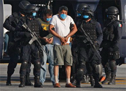 Suspected member of the Gulf Cartel Gregorio Sauceda Gamboa and police wear face masks as a precaution against swine flu during his arrest. (AP Photo/Marco Ugarte)